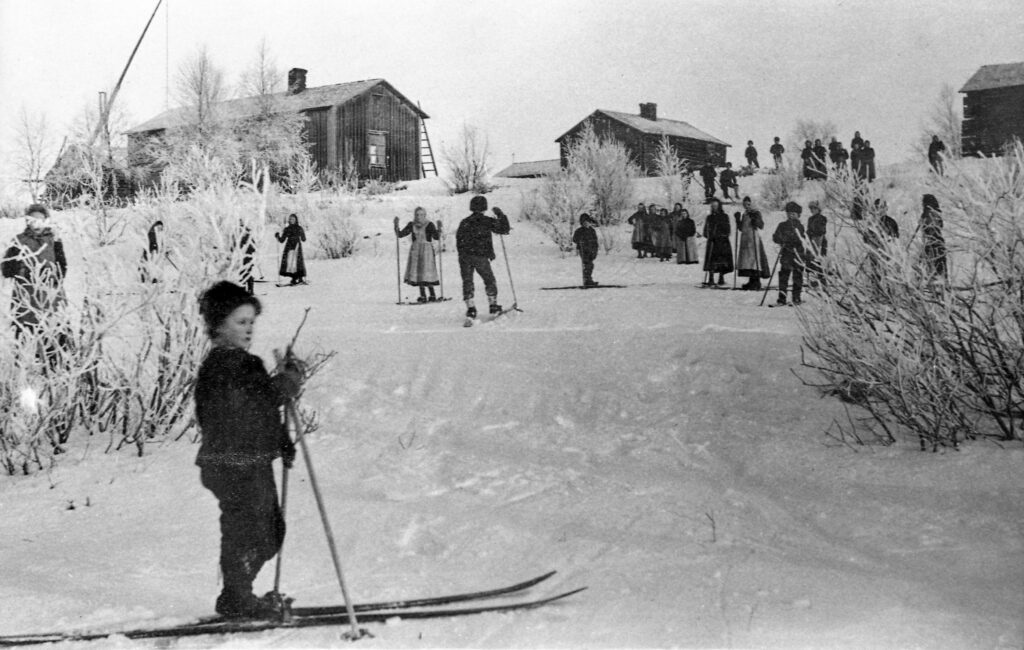 Historisk bild med personer i olika åldrar som åker skidor.